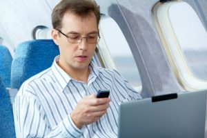 Homem usando um celular dentro do avião (Shutterstock)