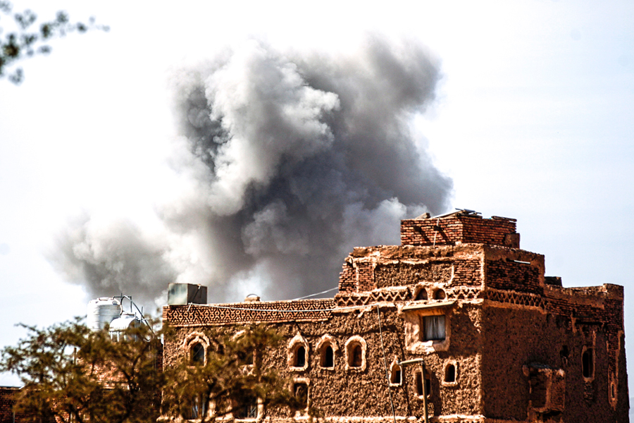 Fumaça sobe atrás de um edifício após um ataque aéreo supostamente da coalizão liderada pela Arábia Saudita, na capital do Iêmen, Sanaa, em 22 de janeiro de 2017. (Mohammed Huwais/AFP/Getty Images)