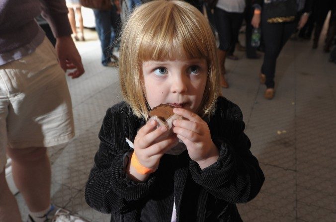 Menina saboreando um alimento durante um evento em Nova York. Estudos recentes mostram que envolver seu filho no processo de cozinhar e comer produtos crus irá beneficia-lo a longo prazo (Michael Loccisano / Getty Images)