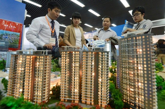 Chineses observam modelos de desenvolvimento imobiliário numa exibição. O conhecido colunista financeiro chinês Niu Dao previu que as bolhas imobiliárias e de ativos provocarão uma crise econômica que derrubará o regime chinês (Mark Ralston/AFP/Getty Images)