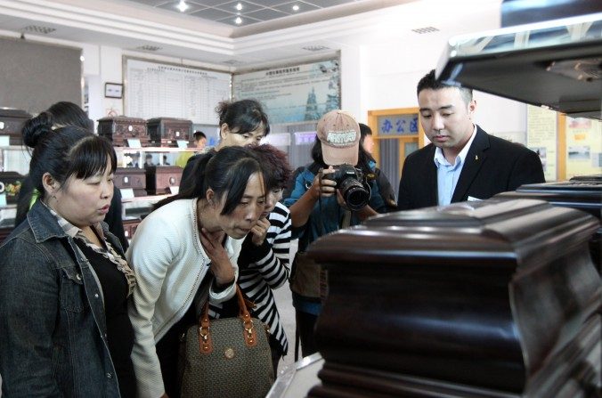 Zhang Jing (2ª à esquerda) escolhe uma urna para guardar as cinzas do esposo Xia Junfeng, um vendedor ambulante de 36 anos que foi executado por matar dois oficiais da polícia urbana e ferir outro em 2009 (ChinaFotoPress/Getty Images)