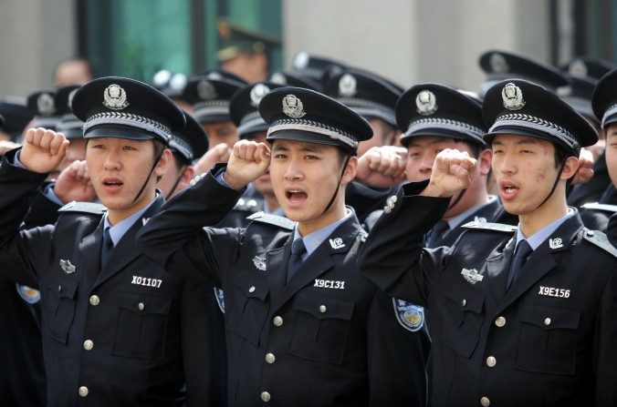 Policiais saúdam a bandeira da República Popular da China. O Partido Comunista lançou recentemente uma campanha de repressão severa contra supostos inimigos da ordem social (ChinaFotoPress/Getty Images)