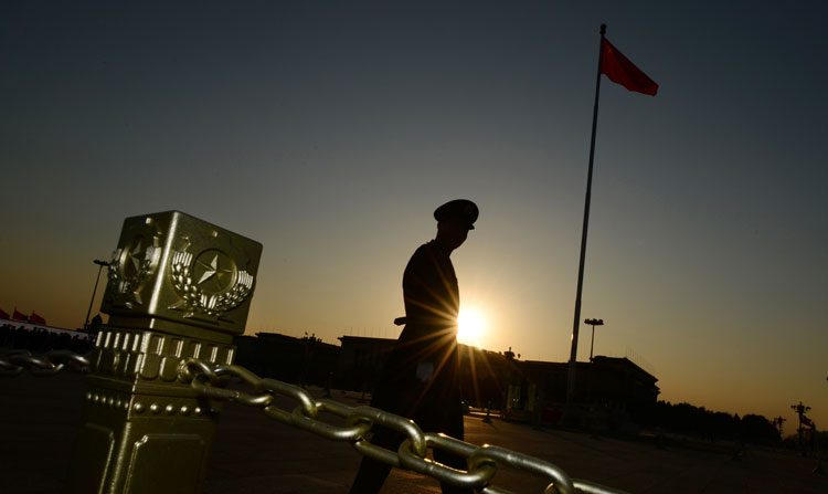 Um policial militar patrulha a Praça da Paz Celestial diante do Grande Salão do Povo durante a 3ª Sessão Plenária do 18º Comitê Central do Partido Comunista Chinês (Mark Ralston/AFP/Getty Images)