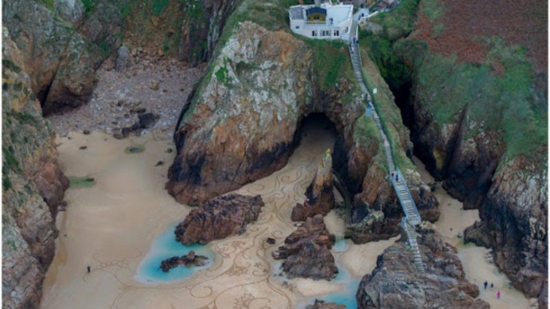 Artista Andrés Amador e seus desenhos na areia de praia (Divulgação)