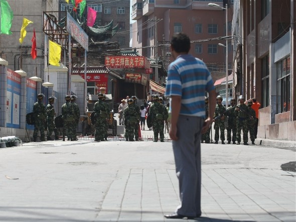 Um ataque à delegacia de polícia de Xinjiang é o último incidente nesta região tumultuada no Noroeste da China. Na foto, um uigur observa policiais chineses numa rua em Urumqi, capital da Região Autônoma de Xinjiang (Guang Niu/Getty Images)