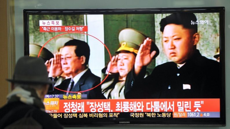 Um sul-coreano assiste um noticiário de TV sobre a deposição de Jang Song-Thaek, tio do líder norte-coreano Kim Jong-Un. Jang está circulado em vermelho no canto esquerdo e Kim Jong-Un, que ordenou sua execução, está à direita (Jung Yeon-Je/AFP/Getty Images)