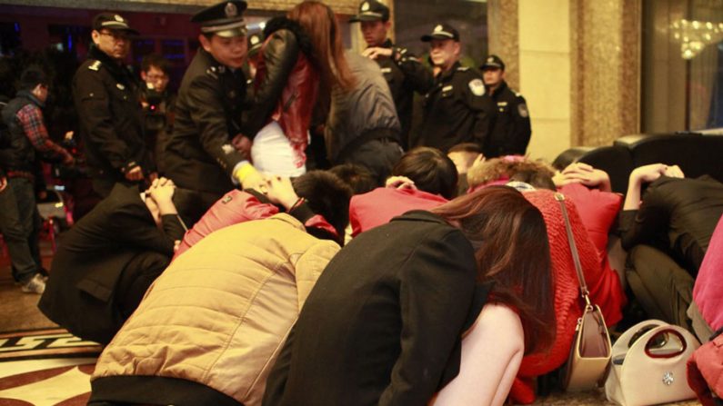A polícia chinesa prende supostas prostitutas e clientes num centro de entretenimento em Dongguan, província de Guangdong, Sul da China, em 9 de fevereiro de 2014. Repressão a vários locais envolvidos no comércio sexual ilegal ocorreu após a CCTV revelar que uma dúzia de hotéis em Dongguan oferecia serviços sexuais (STR/AFP/Getty Images)