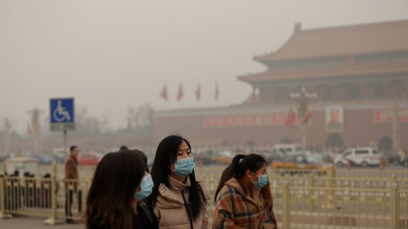 Pessoas caminham na Praça da Paz Celestial usando máscaras na atmosfera densamente poluída de Pequim, capital da China. Emergências hospitalares têm estado lotadas com pessoas recebendo infusões intravenosas e ressurreições (Lintao Zhang/Getty Images)