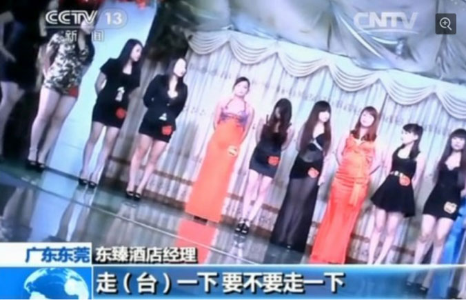 Um grupo de jovens num palco com etiquetas de preço, num hotel em Dongguan, província de Guangdong, em janeiro de 2014. As autoridades recentemente reprimiram a indústria do sexo na cidade (CCTV)