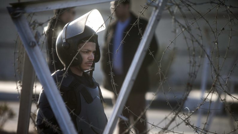 Um policial egípcio faz guarda em frente à Academia de Polícia no Cairo. Líderes militares do Egito anunciam uma aliança com o processo democrático, mas suas ações parecem dizer o contrário (Mahmoud Khaled/AFP/Getty Images)