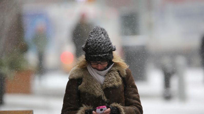 Uma pedestre usa seu smartphone numa nevasca em Nova York. Legisladores querem conter a onda de roubo de telefones celulares com um sistema de desativação remota (John Moore/Getty Images)