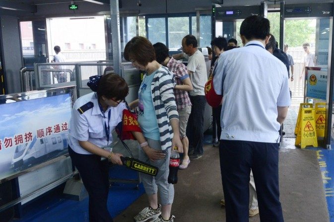 Dois pontos de segurança verificam passageiros numa estação de metrô em Pequim em 26 de maio de 2014. A segurança foi reforçada na capital após um atentado à bomba na província de Xinjiang, Noroeste da China, em 22 de maio (163.com)