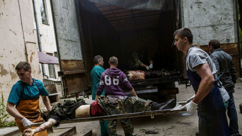 Equipes médicas e ativistas pró-russos descarregam corpos de combatentes pró-russos de um caminhão, na cidade de Donetsk, localizada ao leste da Ucrânia, em 27 de maio de 2014 (FABIO BUCCIARELLI/AFP/Getty Images)