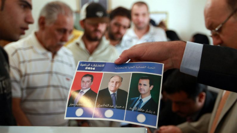 Expatriado sírio vivendo no Iêmen segura uma cédula de voto contendo retratos de futuros candidatos à presidência da Síria: (LR) Maher al-Hajjar, Hassan al-Nouri e o atual presidente da Síria, Bashar al-Assad (MOHAMMED HUWAIS/AFP/Getty Images)