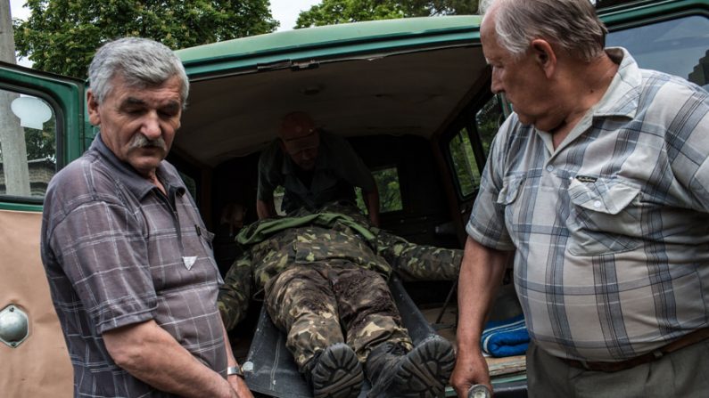 Homens carregam o corpo de um soldado ucraniano morto durante ataque a um posto militar no início do dia 22.05, por forças pró-russas em Volnovakha, Ucrânia. Autoridades relataram que 15 soldados morreram e 31 ficaram feridos no ataque (Brendan Hoffman / Getty Images)