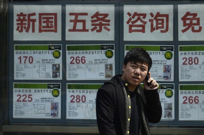 Um chinês fala ao telefone diante de uma agência imobiliária em Pequim. O recém-criado "Índice da Miséria do Comprador de Imóvel" mostra como a habitação está inacessível na China (Wang Zhao/AFP/Getty Images)