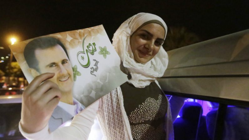 Mulher segura um retrato do presidente reeleito da Síria, Bashar al-Assad, durante comemorações em Damasco depois que ele foi anunciado como o vencedor das eleições presidenciais do país em 4 de junho de 2014 (Joseph Eid/AFP/Getty Images)