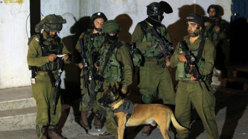 Soldados israelenses tomam posição durante uma incursão no campo de refugiados da Cisjordânia de Jalazon, norte de Ramallah, na manhã de 16 de junho de 2014. O exército diz que mais de 150 palestinos foram detidos na busca dos três jovens sequestrados do bloco de assentamentos Gush Etzion, no sul da Cisjordânia, em 12 de junho. Israel acusa o Hamas de ser responsável (Abbas Momani/AFP/Getty Images)