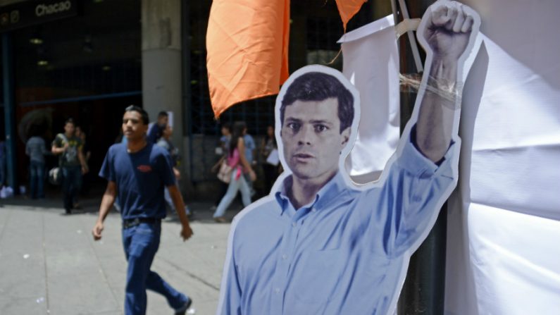 Pessoas passam ao lado de um cartaz com a silhueta do líder da oposição preso, Leopoldo López, em Caracas em 2 de junho de 2014. López, em prisão preventiva há mais de 100 dias, compareceu pela segunda vez no Supremo Tribunal venezuelano que pode vir a sentenciá-lo a até 13 anos de prisão sob a acusação de dano ao patrimônio público, associação para delinquir, incêndio e incitação ao crime (Leo Ramirez/AFP/Getty Images)