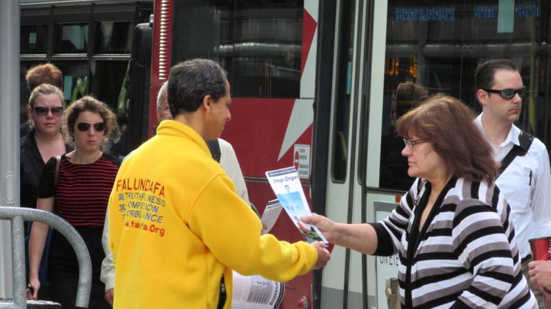 Um praticante do Falun Gong distribui panfletos aos transeuntes, como parte dos esforços dos adeptos da disciplina espiritual para informar o público sobre a perseguição ao Falun Gong na China, que em 2014 marca 15 anos de perseguição à prática, sancionada pelo regime chinês (Epoch Times)