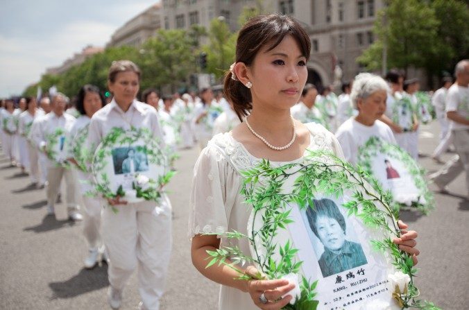 Praticantes do Falun Gong marcham numa parada em Washington DC, EUA, exibindo fotos de vítimas da perseguição que ocorre na China (Epoch Times)