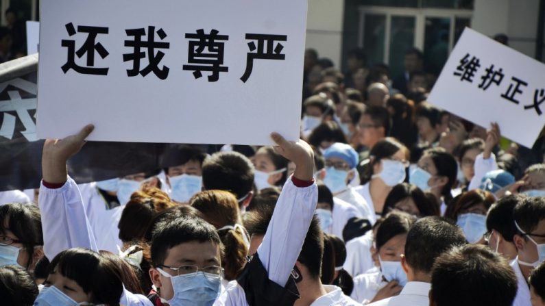 Funcionários hospitalares exibem faixas enquanto protestam contra ataques a trabalhadores médicos, diante do Hospital Popular N. 1 de Wenling, na província de Zhejiang, China, em 28 de outubro de 2013. A relação entre pacientes e hospitais na China tem sido caracterizada pela desconfiança e frequentemente resultado em violência (Jin Yunguo/AFP/Getty Images)