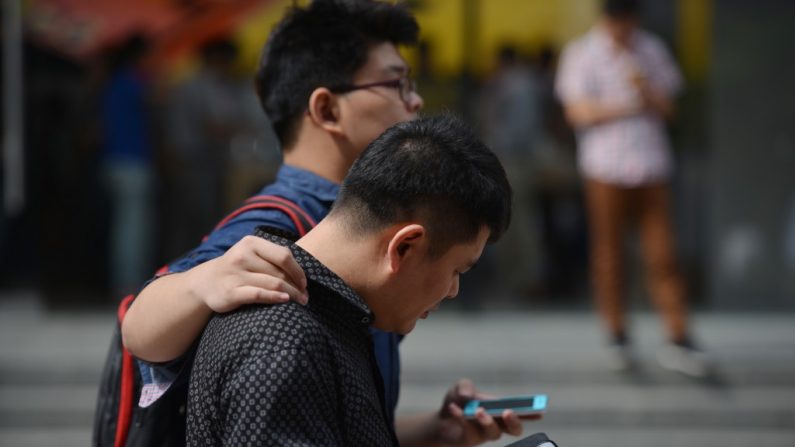 Dois chineses com seus celulares numa rua de Shanghai em 25 de setembro de 2013. Funcionários civis e do Partido Comunista Chinês em Shanghai têm corrido para adquirir telefones celulares criptografados, enquanto uma investigação anticorrupção varre Shanghai (Peter Parks/AFP/Getty Images)