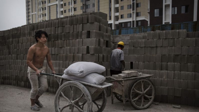 Um operário chinês carrega sacos de cimento num sítio de obras de um novo complexo de apartamentos, em 29 de agosto de 2014, em Pequim, China. O esvaziamento da bolha imobiliária está contribuindo para o declínio no desempenho econômico da China (Kevin Frayer/Getty Images)