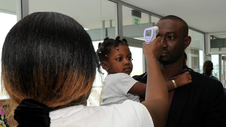 Uma médica do Instituto Nacional de Saúde Pública controla a temperatura de um homem no aeroporto, em Abidjan, na Costa do Marfim, em 13 de agosto de 2014, como parte das medidas de proteção contra o vírus ebola (Sia Kambou/AFP/Getty Images)