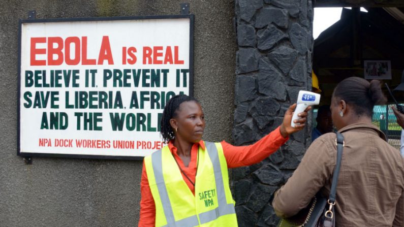 Uma agente de segurança controla a temperatura de uma mulher na entrada do porto de Monróvia em 29 de agosto de 2014. A Organização Mundial de Saúde disse ontem (28) que o número de casos de Ebola foi aumentando rapidamente e que podem exceder 20 mil antes que o vírus seja controlado, com um total de mortes de 1.500 (Dominique Faget/AFP/Getty Images)