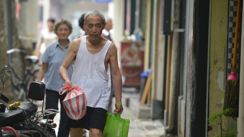 Um idoso carrega sacolas de compras numa rua de Shanghai em 1º de julho de 2013. Enquanto as exportações chinesas desaceleram, o consumo doméstico no país mais populoso do mundo não está falhando em sustentar o crescimento (Peter Parks /AFP/Getty Images)