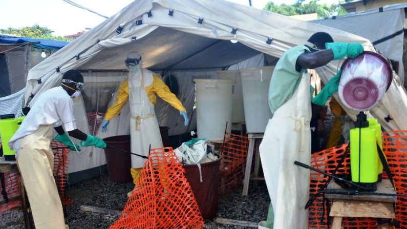 Agente de saúde vestindo uma roupa de proteção é esterilizado ao se juntar aos membros do grupo Médicos Sem Fronteiras perto do principal hospital Donka, em Conacri, em 25 de setembro de 2014 (Cellou Binani/AFP/Getty Images)