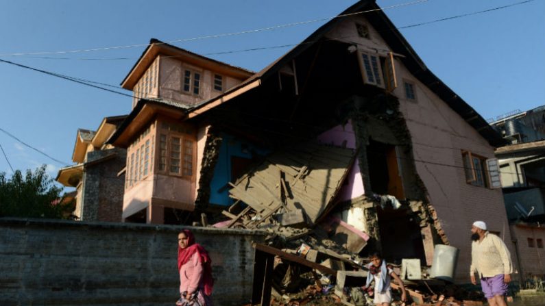 Moradores da Caxemira passam por uma casa danificada pela enchente em Srinagar, em 14 de setembro de 2014. As inundações e deslizamentos de terra já tiraram pelo menos 490 vidas na Índia e no vizinho Paquistão, e as equipes de resgate estão lutando para lidar com a escala do desastre (Tauseef Mustafa/AFP/Getty Images)