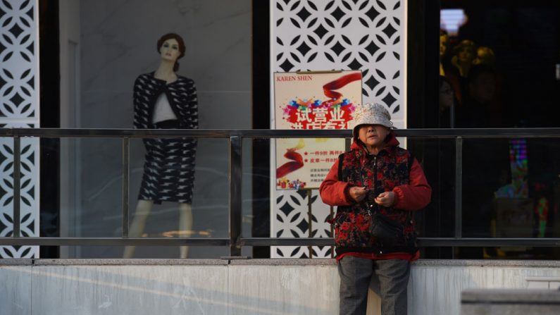 Uma senhora chinesa próxima de uma manequim numa loja de vestuário feminino em Pequim, em 21 de outubro de 2014 (Greg Baker/AFP/Getty Images)