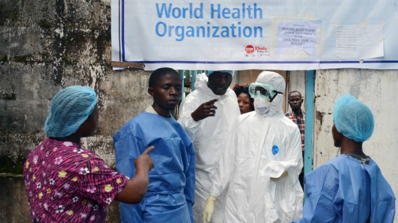 Agentes de saúde com equipamentos de proteção aguardam na entrada da unidade de tratamento de ebola do Centro Médico John F. Kennedy, na capital da Libéria, Monróvia, em 13 de outubro de 2014. Os profissionais de saúde em toda a Libéria entraram em greve na segunda-feira para exigir melhores condições de cuidar dos doentes em meio à violenta epidemia de ebola que já matou dezenas de seus colegas (Zoom Dosso/AFP/Getty Images)