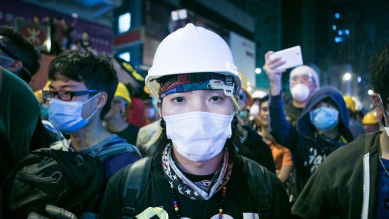 Um manifestante com aparatos de proteção se posiciona na linha de frente diante de policiais em Mong Kok, Hong Kong, em 5 de novembro de 2014 (Benjamin Chasteen/Epoch Times)