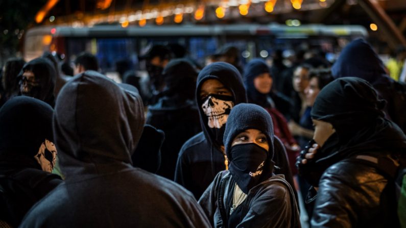 Elizabeth (nome verdadeiro foi omitido, para proteger sua identidade, 2º dir.), 21, participa com outros membros do grupo Black Bloc em um protesto contra a Copa do Mundo da FIFA em uma favela na zona norte do Rio de Janeiro, Brasil, em 30 de maio de 2014. Elizabeth vive com seu pai após a morte da mãe e trabalha como técnica de laboratório em um hospital (Yasuyoshi CHIBA / AFP / Getty Images)