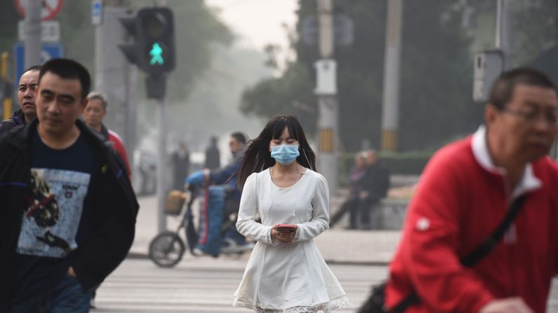 Uma mulher usa máscara num dia poluído em Pequim, em 20 de outubro de 2014. Pequim retomou a sua vida normal após o encerramento das reuniões da APEC em 12 de novembro de 2014, enquanto peticionários detidos foram liberados, o aquecimento foi restabelecido, as operações das fábricas foram retomadas, as restrições sobre automóveis foram suspensas e assim por diante (Greg Baker/AFP/Getty Images)