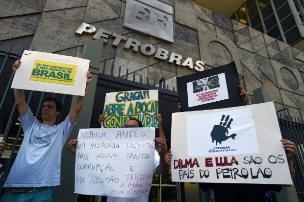 Manifestantes seguram cartazes durante um protesto contra a corrupção do lado de fora da gigante estatal de petróleo Petrobras no Rio de Janeiro em 16 de dezembro de 2014 (VANDERLEI ALMEIDA/AFP/Getty Images)