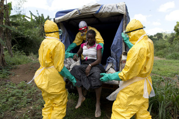 Membros de uma equipe de saúde usando roupas de proteção ajudam um paciente com suspeita de ebola em seu caminho para um centro de tratamento Ebola administrado pela Cruz Vermelha Francesa em Patrice, perto de Macenta, em 21 de novembro de 2014 (KENZO Tribouillard/AFP/Getty Images)