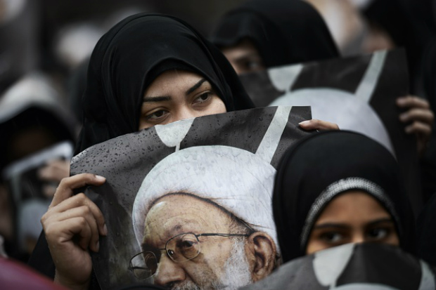 Mulheres de Bahrein seguram imagens do principal clérigo xiita sênior do país, Sheikh Isa Qassim, durante um comício anti-governo, em apoio ao Qassim na aldeia de Diraz, a oeste da capital Manama, em 28 de novembro de 2014 (Mohammed al-SHAIKH/AFP/Getty Images)