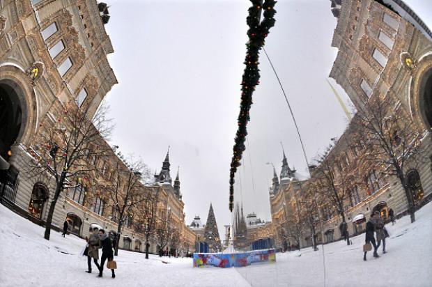 Imagens de pedestres são refletidas na fachada de vidro de uma feira de Natal na Praça Vermelha de Moscou em 25 de dezembro de 2014 (YURI KADOBNOV/AFP/Getty Images)