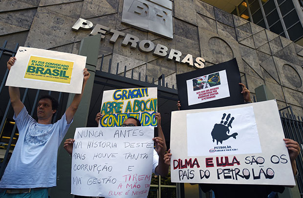 Ativistas seguram cartazes durante protesto contra o esquema de corrupção - Petrolão - em frente da sede da Petrobras no Rio de Janeiro (Vanderlei Almeida / AFP / Getty Images)