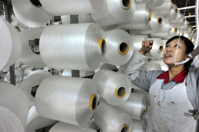 Uma trabalhadora chinesa verifica uma máquina de fazer cobertores para exportação numa fábrica em Yiwu, província de Zhejiang, em 12 de janeiro (STR/AFP/Getty Images)