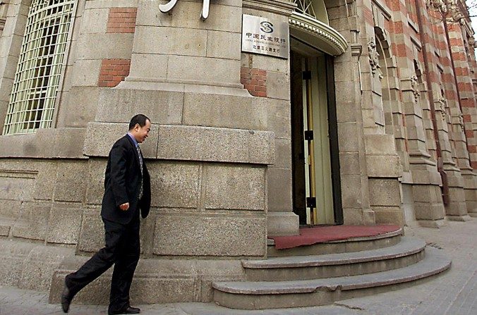 Um chinês caminha diante da sede do Banco Minsheng, o maior banco privado da China, em Pequim, em 25 de fevereiro de 2002. Em 31 de janeiro, a mídia chinesa informou que Mao Xiaofeng, o presidente do banco, foi detido numa investigação de corrupção (AFP/Getty Images)