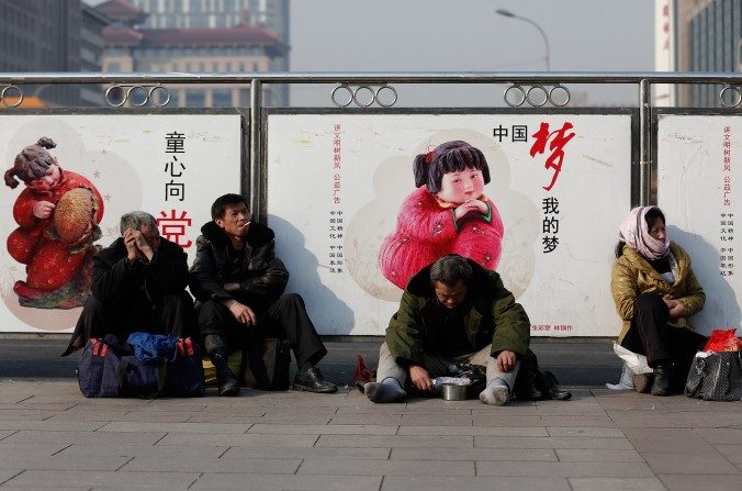 Um mendigo sentado na frente de uma propaganda de governo. As economias desenvolvidas são baseadas em uma ampla classe-média, precisamente o que não ocorre na China (Lintao Zhang / Getty Images)