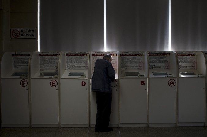 Homem consulta o preço das ações numa firma de corretagem de Pequim (AP Photo/Andy Wong)