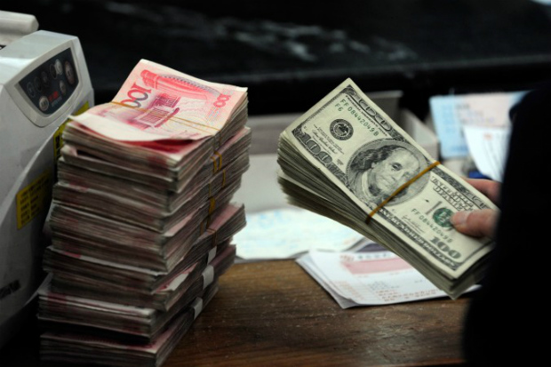 Bancário chinês prepara-se para contar uma pilha de dólares norte-americanos junto com pilhas de 100 notas de yuan chinês em um banco em Hefei, província de Anhui, em 9 de Março de 2010 (STR/AFP/Getty Images)