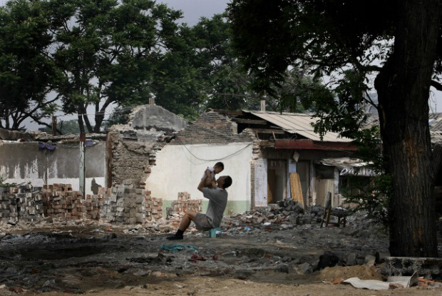 Chinês brinca com seu filho perto de sua casa parcialmente demolida em Pequim no domingo, 8 de junho de 2008. Pequim, uma das cidades fabulosas da antiguidade, está experimentando reconstruções para apresentar um visual mais moderno para os próximos Jogos Olímpicos de Verão. (AP Photo/Andy Wong)