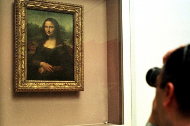Homem tira foto da Mona Lisa, por trás de um vidro de proteção no museu do Louvre, em Paris. (AP Photo/Amel Pain, File)